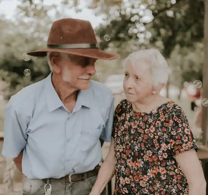 Casal de trabalhadores rurais idosos sorrindo no campo, representando a aposentadoria rural