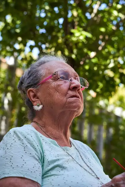 Idosa de óculos olhando para o alto, pensativa, com dúvidas sobre qual modalidade de aposentadoria escolher