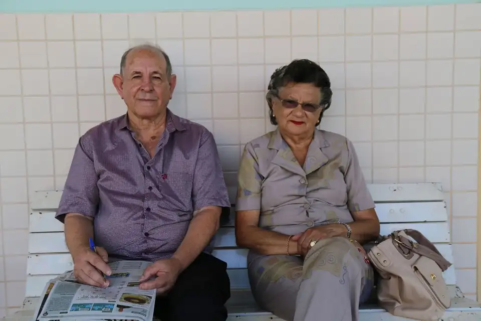 Casal de idosos sentado em um banco, aguardando atendimento para o pedido de aposentadoria no INSS